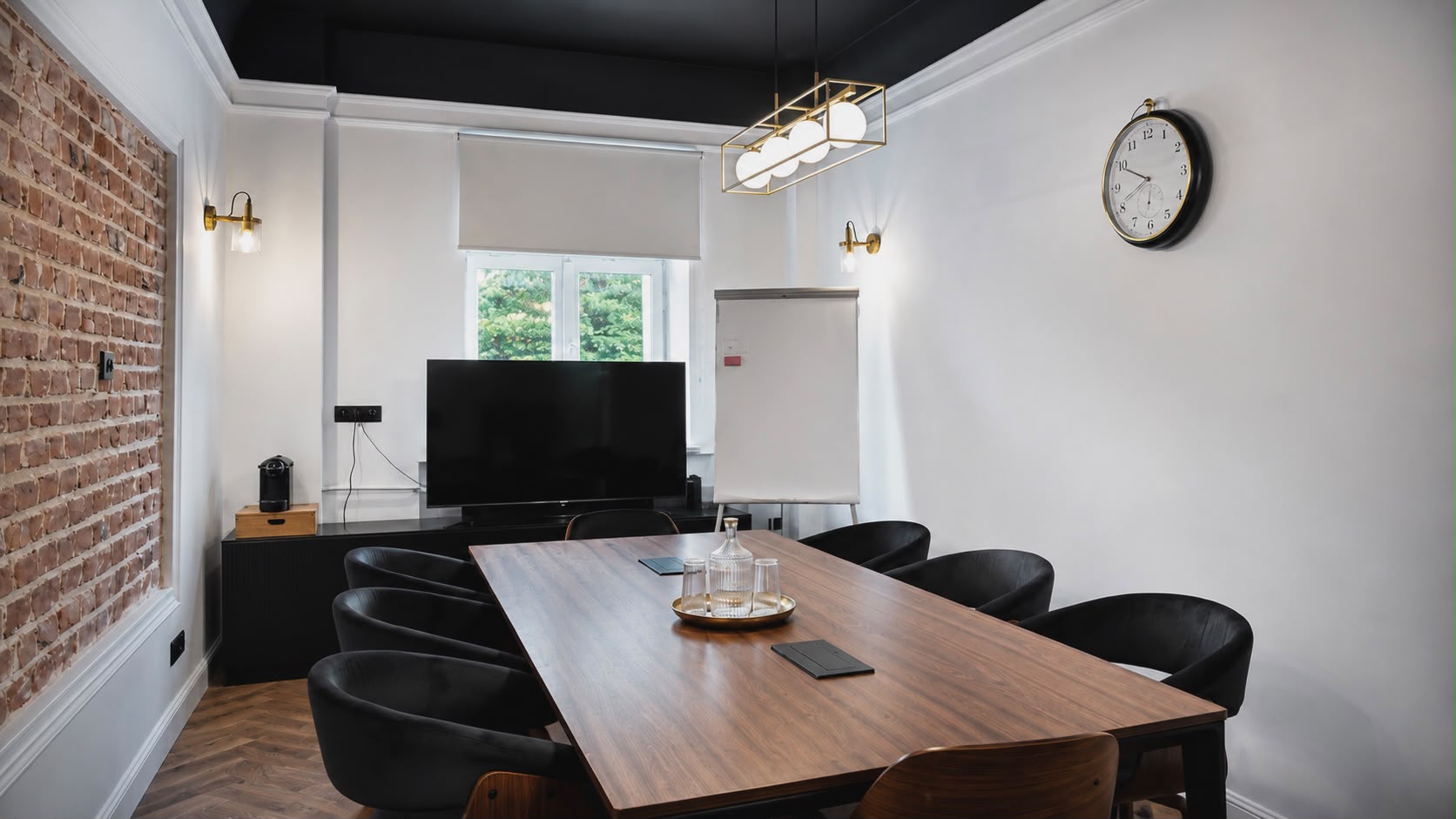 Sala konferencyjna z kontrastową ścianą z cegły, dużym zegarem i limonkowymi krzesłami